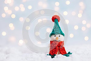 Christmas background with a snowman in a green hat and a red scarf. Greeting card with a happy toy snowman. Happy New Year. Space