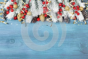 Christmas background with snowy fir tree and holiday decorations on blue wooden table top view. Greeting card with space for text.