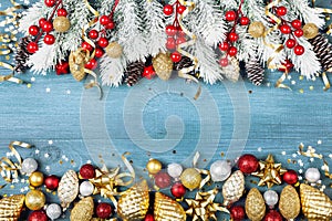 Christmas background with snowy fir tree and shiny holiday decorations on blue wooden table top view. Greeting card.