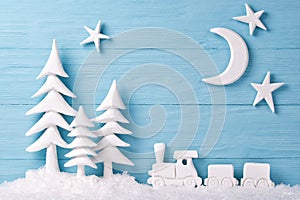 Christmas background with white Christmas trees, toy train, snow, moon and stars, blue wooden background