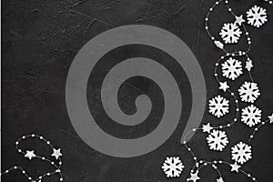 Christmas background: white snowflakes and garland on the black background. Top view. Flat lay