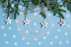 Christmas background with white snowflakes, stars, fir branches on pastel blue. Greeting card. Winter concept. Happy new year