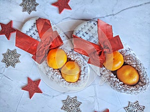 Christmas background of white soft home slippers and red decoration and orange tangerines. Flat lay. New Years gift ideas.