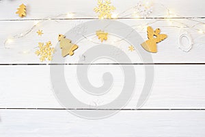 Christmas background on a white wooden background with a gold angel and a Christmas tree and a garland, top view
