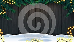 Christmas background, wooden fence of boards with frame of Christmas tree branches, garland of yellow bulb lights and snow.