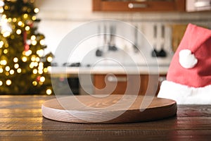 Christmas background with wooden table top, Santa hat, and blurred holiday decorating kitchen