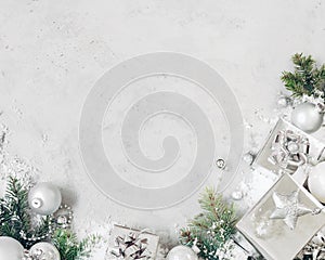 Christmas background with xmas decorations. Silver christmas gift, fir tree branch and baubles ornaments on gray stone table.