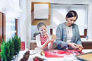 Christmas bakery. Mother and daughter making gingerbread, cutting cookies of gingerbread dough.
