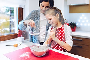 Christmas bakery. Mother and daughter making gingerbread, preparing eggs, flour and honey for gingerbread dough.