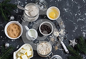Christmas baking background. Flour, sugar, butter, rolled oats, eggs, chocolate chips on a dark background.