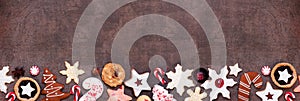 Christmas baking bottom border with an assortment of cookies and sweets on a dark stone banner background