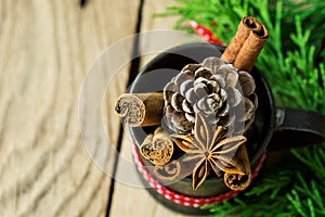 Christmas Baking Ingredients Cinnamon Sticks Anise Star Cloves Pine Cone in Vintage Jug with Red Ribbon Juniper Twigs on Wood