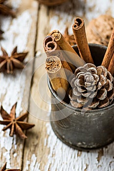 Christmas Baking Ingredients Cinnamon Sticks Scattered Anise Star Walnuts Pine Cone in Vintage Jug on Wood Background. Postcard