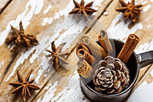 Christmas Baking Ingredients Decoration Cinnamon Sticks Scattered Anise Star Pine Cone in Vintage Jug on Snowy Wood Background.