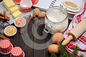 Christmas baking ingredients â€“ muffin molds, spices, butter, eggs and flour on dark wooden background