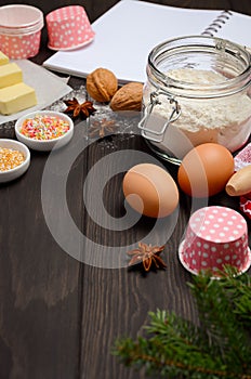 Christmas baking ingredients â€“ muffin molds, spices, butter, eggs and flour on dark wooden background