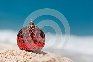 Christmas Ball colored Red on the Sandy Beach, Holiday and Vacation Concept