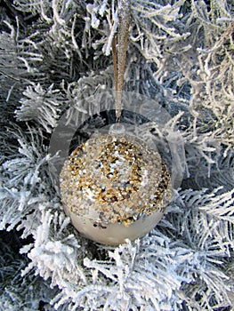 Christmas ball decorated with gold sequins handing on white tree