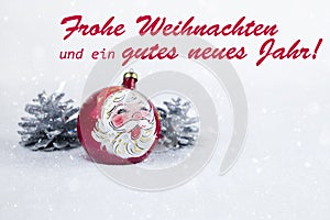 Christmas ball with drawing of Santa Claus and pines with text in German `Frohe Weihnachten und ein gutes neues Jahr`