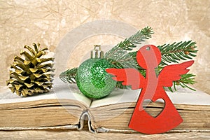 Christmas ball, fir-tree branch, red Angel, golden pinecone and old book