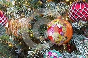 Christmas ball with floral ornament on Christmas tree with garland. Handmade Christmas decorations