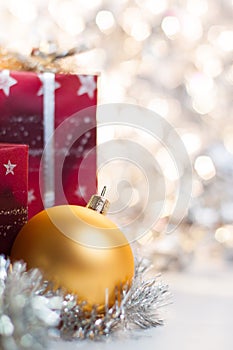 Christmas ball and gifts on light background