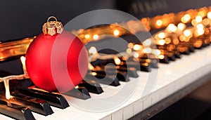 Christmas ball and lights on a piano keyboard