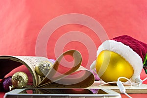 Christmas ball with Santa's hat and earphones, music notation book with pages shaping heart