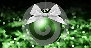 Christmas ball, silver satin ribbon bow on blurred green bright