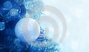 Christmas ball on a Christmas tree branch, closeup, soft selective focus. Blue christmas background with balls