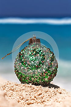 Christmas ball on yellow sand at tropical beach and sea, holiday
