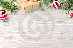 Christmas balls, box with a gift and Christmas tree branches on white wooden table