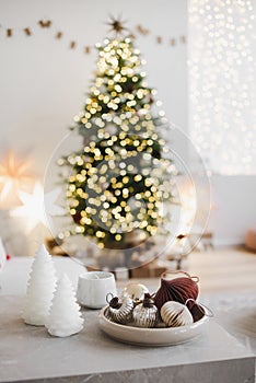Christmas balls and decorations on table over defocused magic interior with christmas tree, stars and gifts at the background