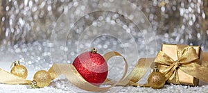 Christmas balls and gift box, golden ribbon and snow, abstract bokeh lights background