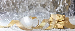 Christmas balls and gift box, golden ribbon and snow, abstract bokeh lights