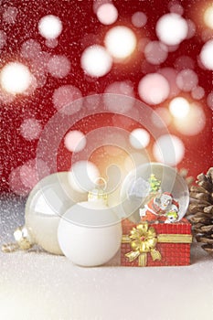 Christmas balls, Santa Claus in a Snow globe, and Pine cones on a Cream-Colored Cloth, set Against a Red Background and exquisite