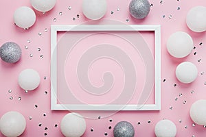 Christmas balls, sequins and picture frame on stylish pink table top view. Fashion background. Flat lay. Party mockup.