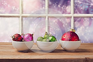 Christmas balls on wooden table over window dreamy background