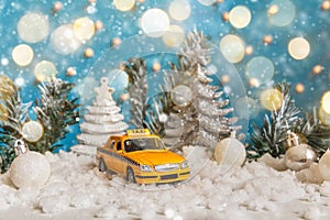 Christmas banner Background. Yellow toy car Taxi Cab model and winter decorations ornaments on blue background with snow