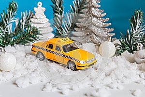 Christmas banner Background. Yellow toy car Taxi Cab model and winter decorations ornaments on blue background with snow