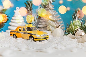 Christmas banner Background. Yellow toy car Taxi Cab model and winter decorations ornaments on blue background with snow