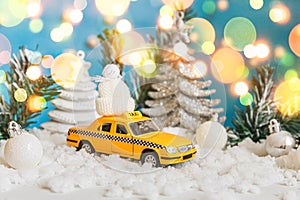 Christmas banner Background. Yellow toy car Taxi Cab model and winter decorations ornaments on blue background with snow