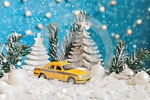 Christmas banner Background. Yellow toy car Taxi Cab model and winter decorations ornaments on blue background with snow