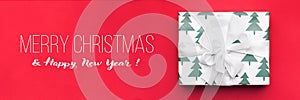 Christmas banner. Beautiful christmas gift isolated on red background. Wrapped xmas box. Gift wrapping.