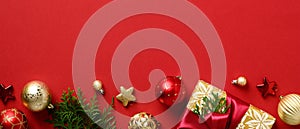 Christmas banner design. Row of Xmas decorations, gold and red baubles, fir branches, gift box on red background. Christmas header