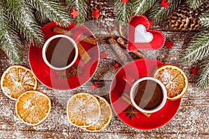 Christmas banner with green tree, cones, red cups with hot chocolate, orange and cinnamon on brown wooden background