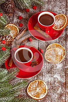 Christmas banner with green tree, cones, red cups with hot chocolate, orange and cinnamon on brown wooden background