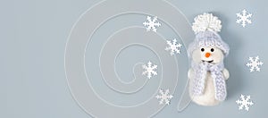 Christmas banner with white snowflakes and a cute snowman on a pastel blue background. Copy space, top view, flat lay