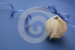 Christmas bauble with blue ribbon, isolated over blue background. Classic blue abstract background. Copy space