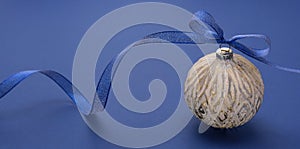 Christmas bauble with blue ribbon over blue background. Bannner. Winter holidays greeting card. Minimal concept. Color of the year
